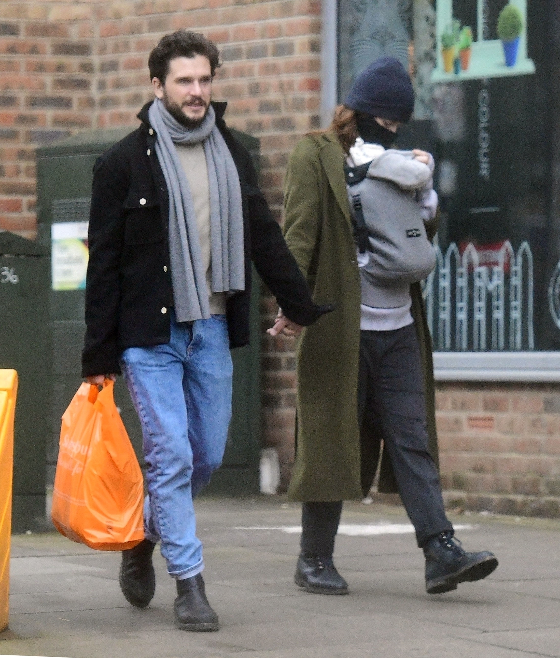 Kit Harington holds wife Rose Leslie's hand as she appears to carry a newborn in a baby carrier.