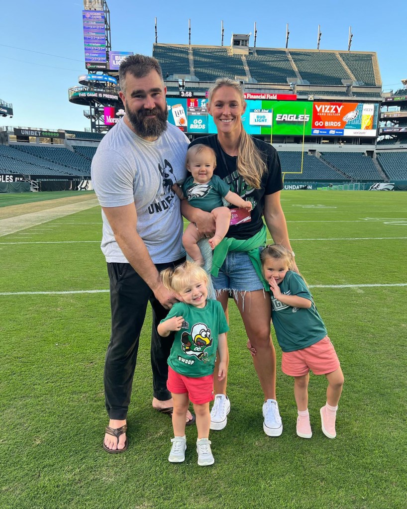 Jason Kelce and Kylie Kelce on the football field with their three daughters. 