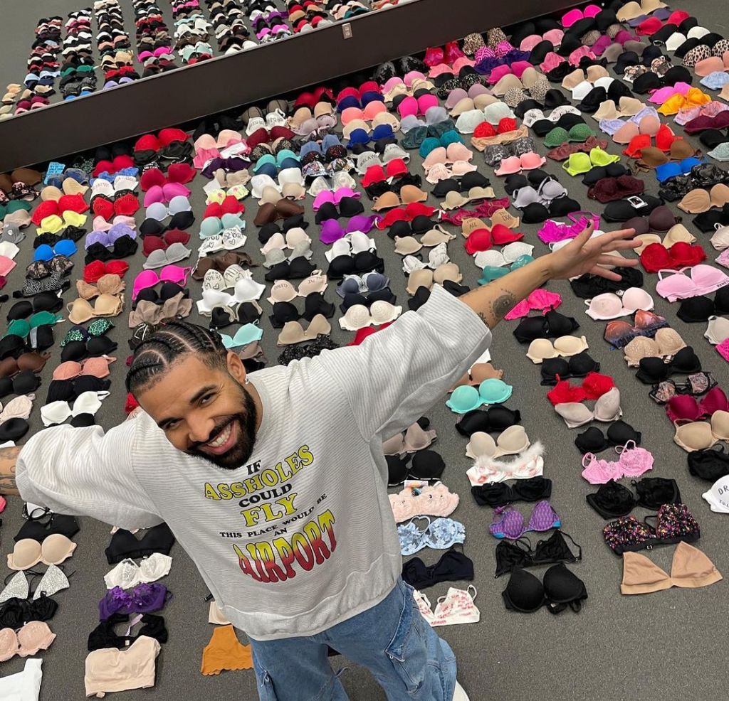 Drake posing in front of several bras.