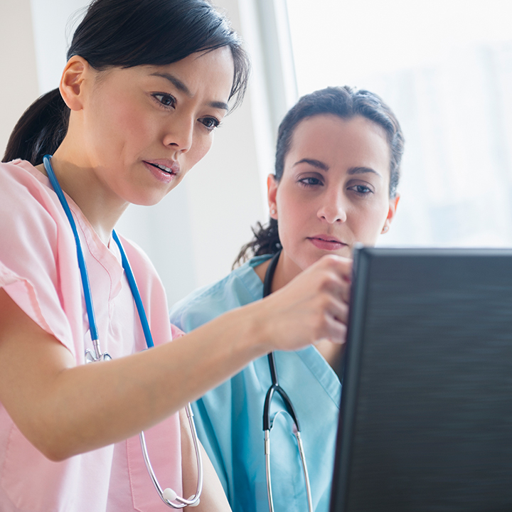 Two female skilled nursing providers reviewing data on a desktop computer together