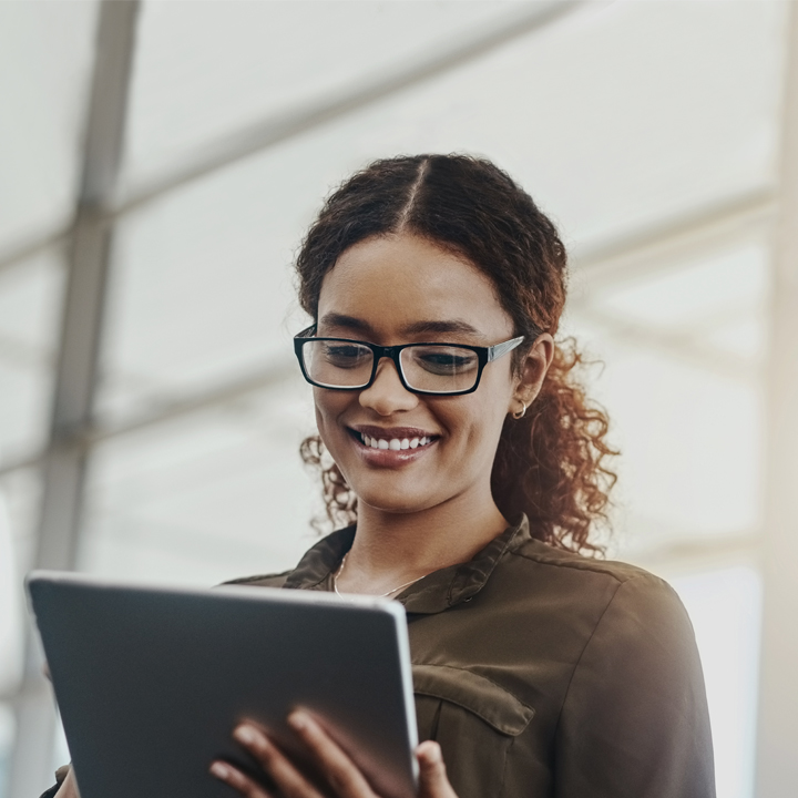 Female smiling as she looks down at value-based care content on a tablet device