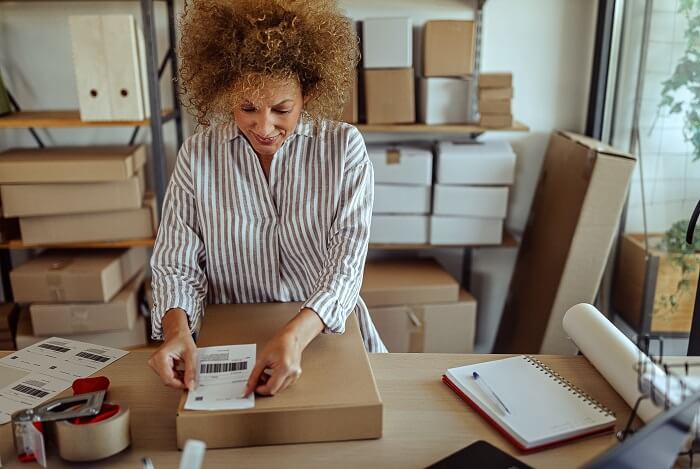 Frau nutzt YourGLS und klebt ein Paketlabel auf Ihr Paket