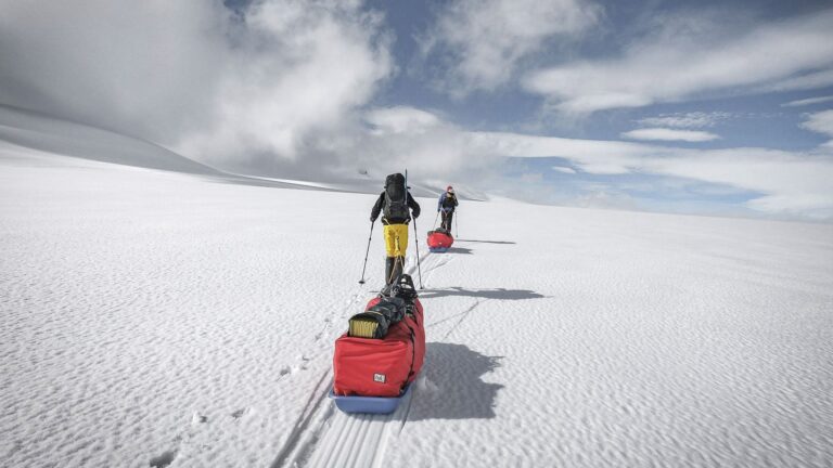 Photo of two people pulling sleds across a snowy landscape.