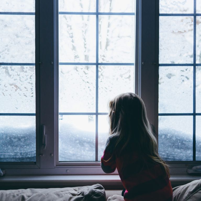 Little girl looking out window at snow