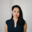 Brunette woman looking into camera against a white background.