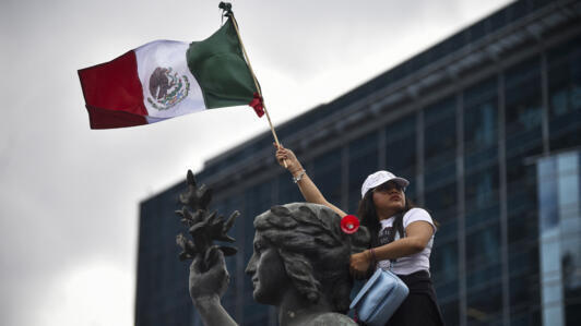 A member of the National Association of Magistrates and District Judges holds a Mexican flag as she takes part in a protest.