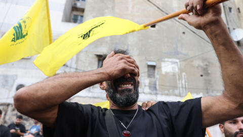 A man reacts while holding a Hezbollah flag during the funeral of people killed after hundreds of paging devices exploded in a deadly wave across Lebanon the previous day, in a south Beirut district, on September 18, 2024.