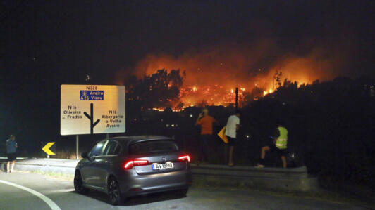 Pessoas param na estrada para observar os incêndios perto de Sever do Vouga, uma cidade no norte de Portugal que foi cercada por incêndios florestais, na noite de segunda-feira, 16 de setembro de 2024.