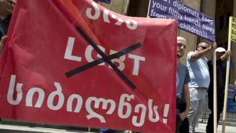 Activistas de extrema derecha georgianos sostienen una pancarta en la que se lee "No a las tinieblas LGBT" durante una concentración frente al Parlamento en Tiflis el 2 de julio de 2022.