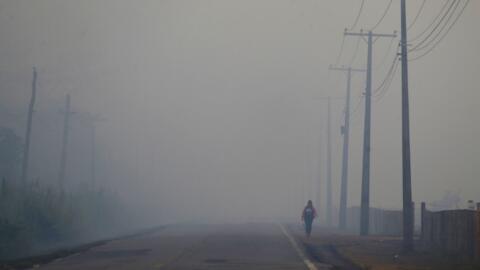 Uma pessoa caminha na rodovia BR-319 em meio à fumaça de um incêndio florestal que atinge Careiro Castanho, no estado do Amazonas, em 6 de setembro de 2023.