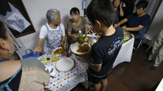 Un băiat toarnă curry pe o farfurie la o „cafenea pentru copii” înființată de Misako Omura în Tokyo, la 18 august 2016. 