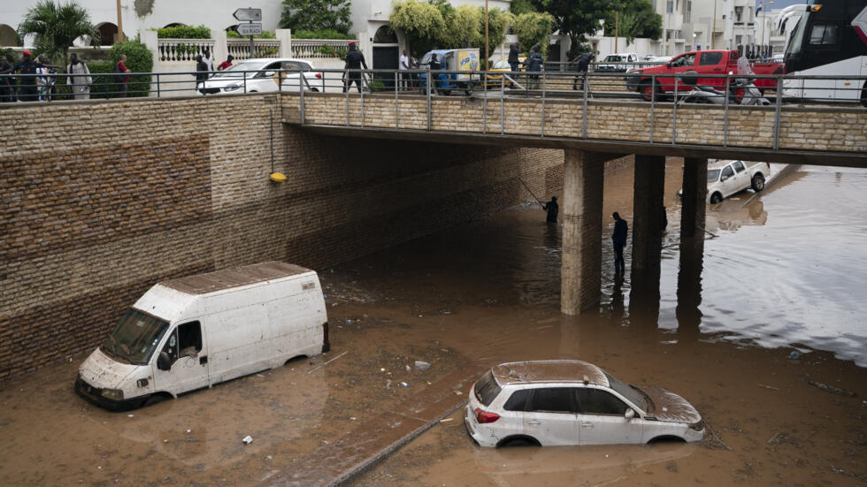 Des hommes se tiennent dans l’eau de crue à côté de voitures partiellement submergées après une forte pluie à Dakar, au Sénégal, le vendredi 5 août 2022. (Image d'illustration).