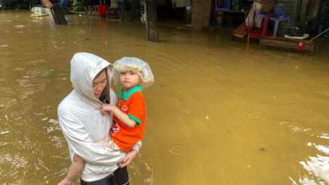 Une femme tient un garçon dans ses bras alors qu'elle patauge dans une rue inondée suite à l'impact du typhon Yagi, dans la ville de Thai Nguyen, au Vietnam, le 11 septembre 2024