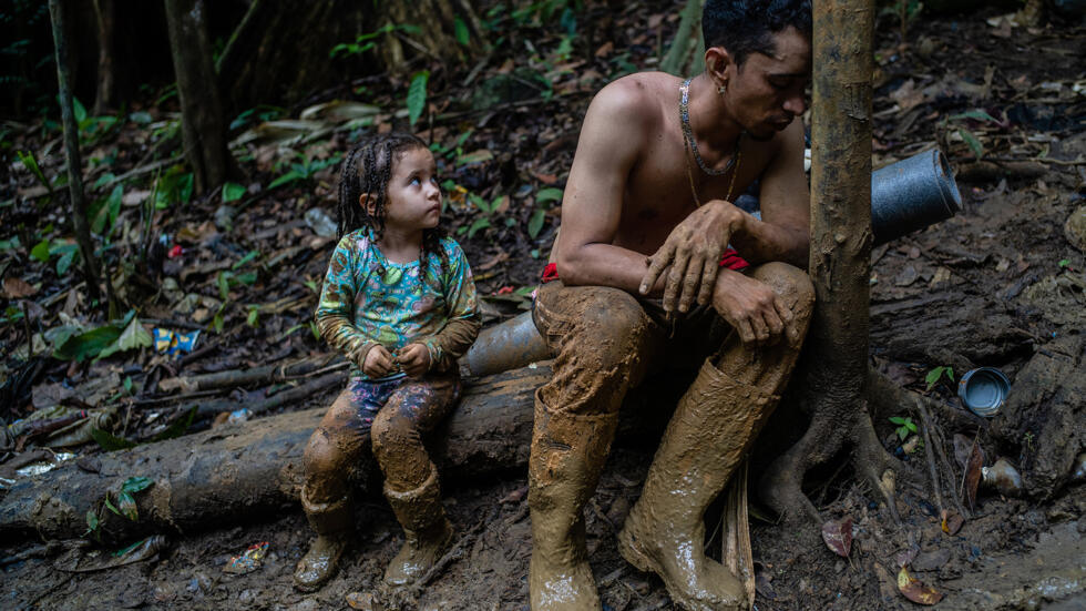 El migrante venezolano Luis Miguel Arias (28) con su hija Melissa (4) descansan mientras suben una colina en el Tapón del Darién, entre Colombia y Panamá. Cruzó el Paso con su mujer, sus dos hijos y un amigo.