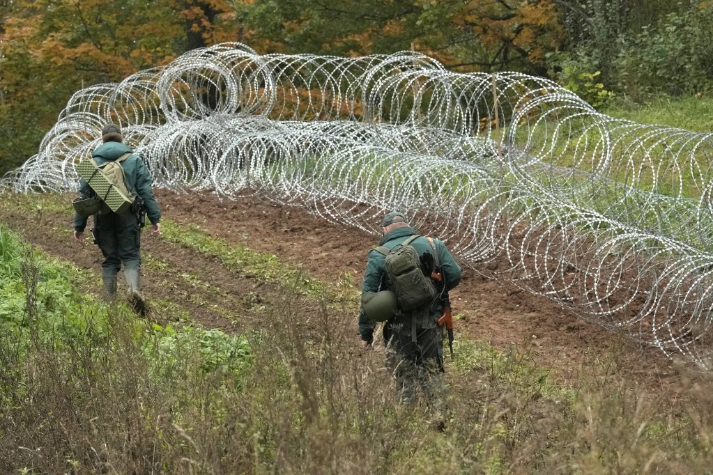 Latvian border guard walks past barbed wire temporary fence on the Latvian-Belarus border near Robeznieki, Latvia, September 28, 2021. REUTERS/Ints Kalnins