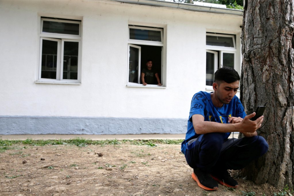 Photo used as illustration: A migrant uses a phone in a migrant reception center | Photo: Andrej Cukic /  EPA