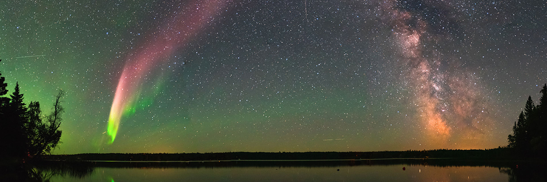 Greenish blue night sky with colorful swirls streaming down in two places