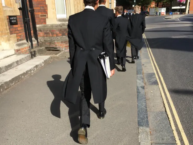 Etonian schoolboys, from the English independent boarding school, Eton College, dressed in traditional uniform of tails, going to class in the famous, historic town of Eton in Windsor, England