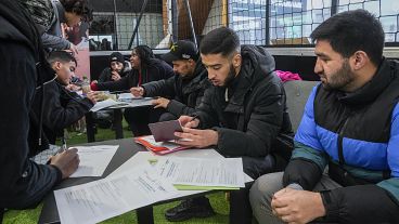 Arbeitssuchende füllen die Papiere aus, während sie sich für Sicherheitsjobs während der Olympia-Jobmesse im Sportzentrum in Paris bewerben, Donnerstag, 14. Dezember 2023