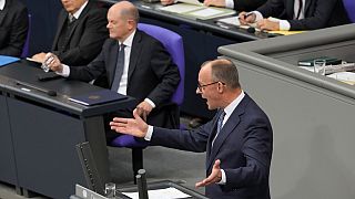 Opposition leader Friedrich Merz, right, of CDU speaks as German Chancellor Olaf Scholz, centre, looks on during a plenary session at the German parliament Bundestag.