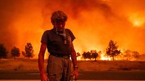 Grant Douglas pauses while evacuating as the Park Fire jumps Highway 36 near Paynes Creek in Tehama County, California.