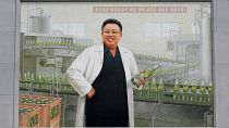 En la entrada de la fábrica de cerveza Taedonggang, en Pyongyang, se ve un mural del difunto líder norcoreano Kim Jong Il con una bata blanca de laboratorio sosteniendo una botella de cerveza, 