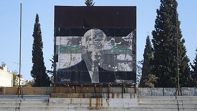 Un cartel dañado del difunto presidente sirio Hafez al-Assad se ve por encima de las gradas del estadio utilizado como puesto militar en Damasco, 19 de diciembre de 2024.