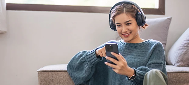 Frau hält Smartphone in der Hand und hört Musik.