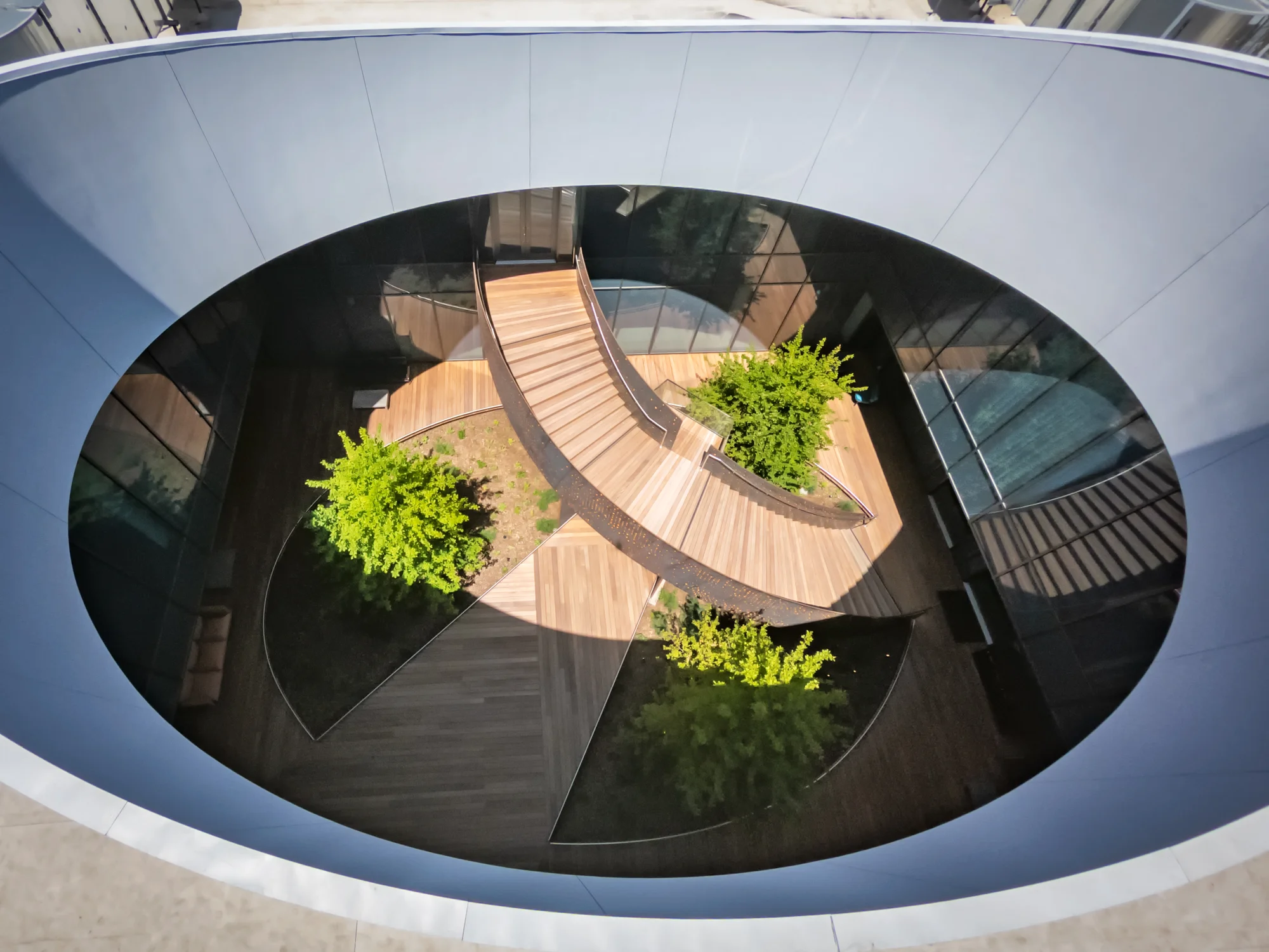 An image of the courtyard is framed by an oval shape that looks down into the sun-filled courtyard that shows paved walkways, an outdoor staircase and landscaping.