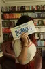 Ariel holding up a license plate reading "BOOOKS" to cover up her face