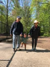 Tony’s parents and Owen all holding hands walking down a sidewalk together with trees in the background.