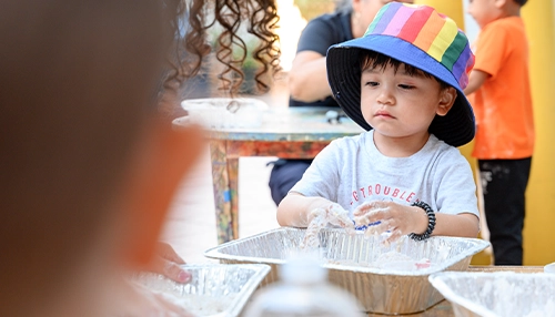 child playing with cookie flour on aluminum tray