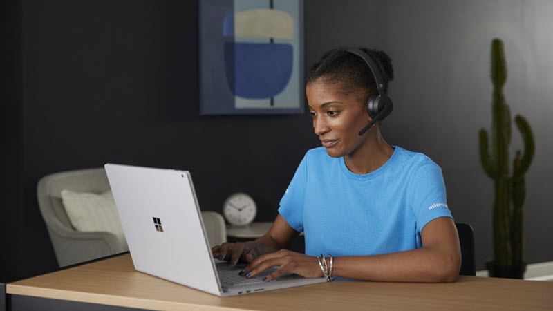 Frau, die ein Headset trägt, während sie einen Laptop verwendet