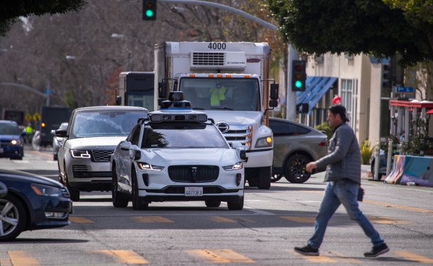 A white, autonomous Waymo car on the road in San Francisco.