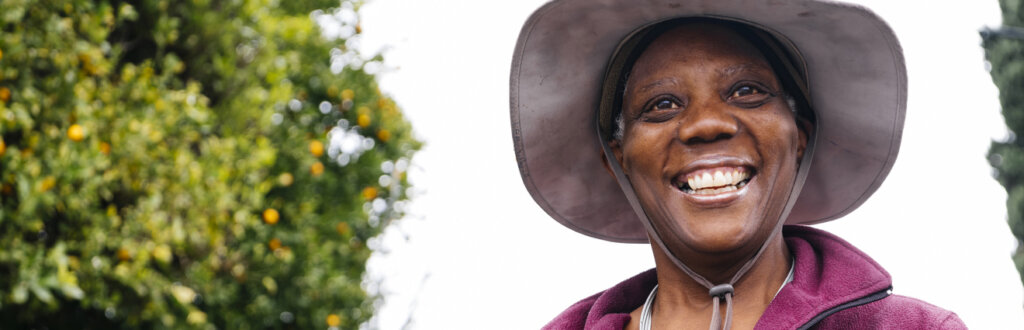 smiling retiree wearing a hat while gardening