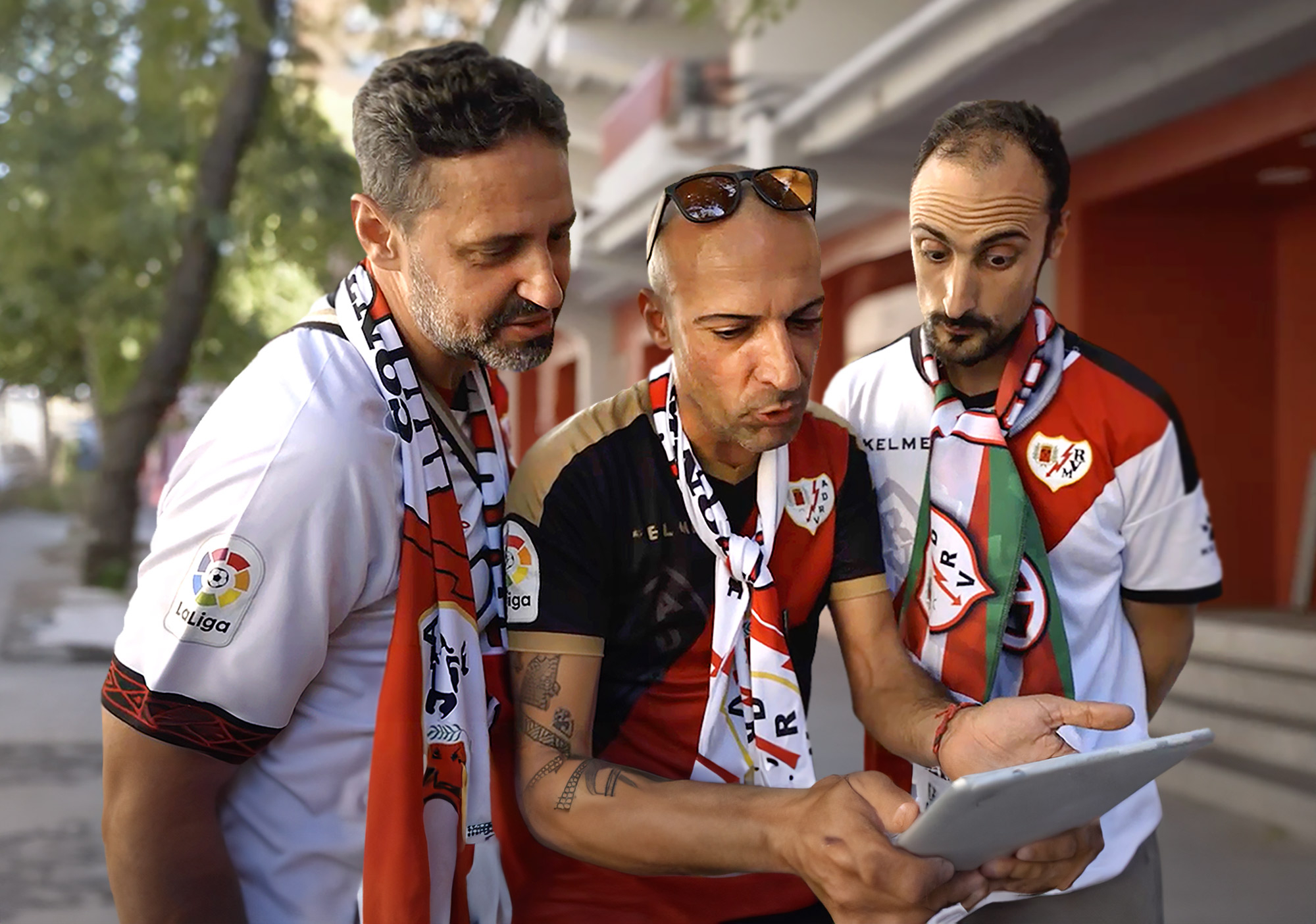 Three men looking at a tablet while standing on a street.