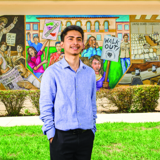 Student in front of a mural