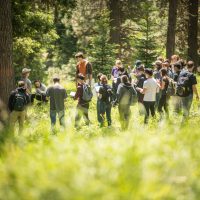 Students gathered around in a circle, on a field trip in a forest