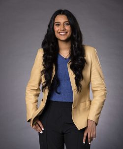 Portrait of Aisha Rasid in light yellow jacket against a gray background