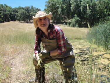 A picture of Chelsea Wood on one knee, smiling at the camera.