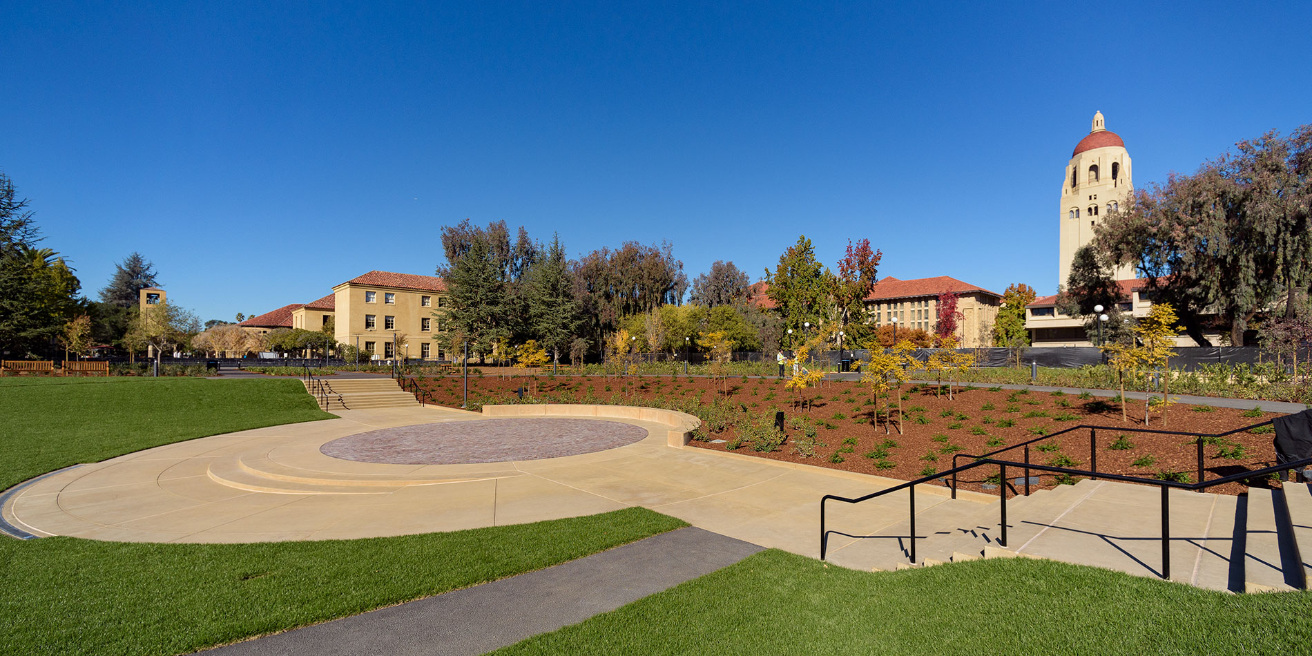 View of Meyer Green, a landscaped bowl featuring gentle grassy slopes surrounded by trees, with Hoover Tower in background.