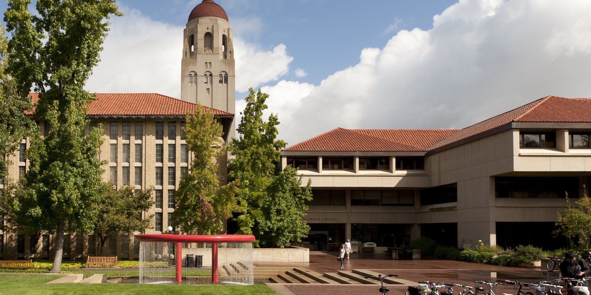 Green Library against a cloudy sky with Shumway Fountain in the foreground and Hoover Tower in the background. Credit: Linda A. Cicero / Stanford News Service