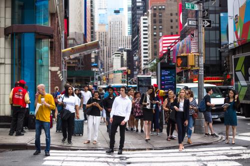 NEW YORK CITY - JULY 26, 2018: Busy sidewalk in Times Square in Manhattan crowded with many people crossing street and billboards.