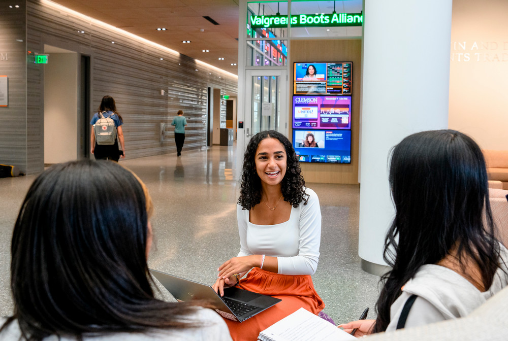 Three students walking in college building.