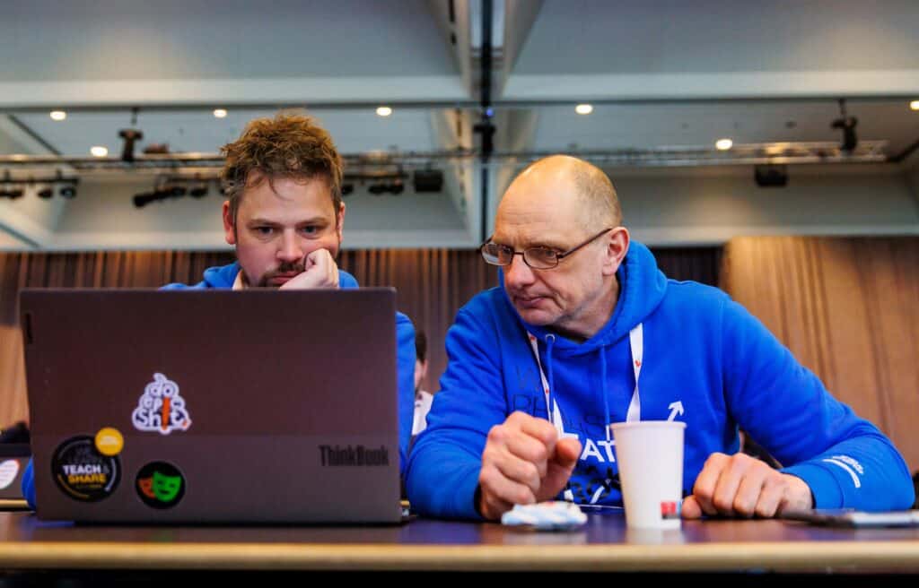 Two people looking at a laptop, one appears to be teaching the other something