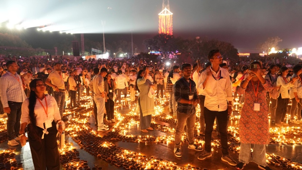 People stand in between rows of lit earthen lamps on the banks of the Saryu river during Deepotsav celebrations, an event organized by the Uttar Pradesh state government on the eve of Diwali, in Ayodhya, India, Wednesday, Oct. 30, 2024. (AP Photo/Rajesh Kumar Singh)