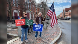 Residents in Portsmouth, New Hampshire hold elections signs and an American flag on Nov. 5, 2024.