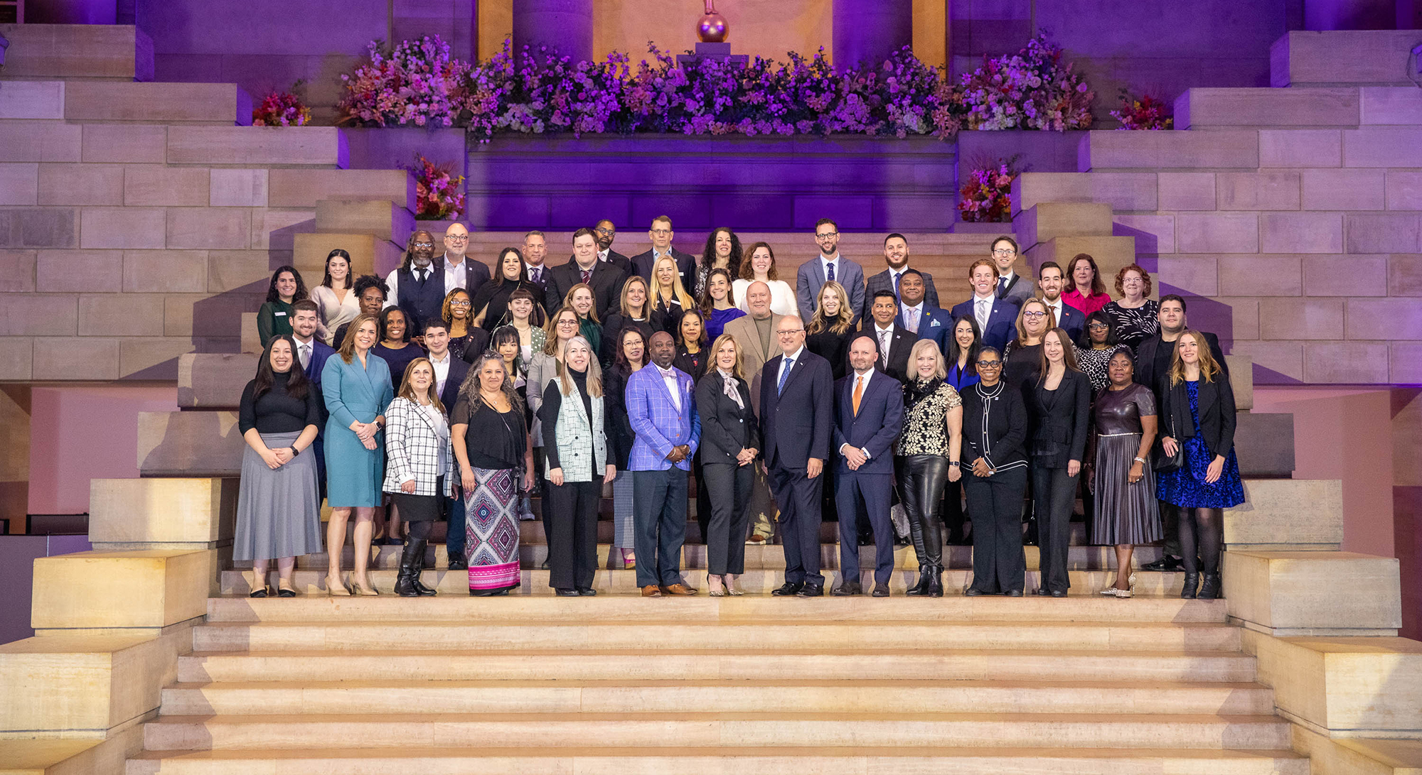 A large group of people stand at the top of a staircase to pose for a photo.