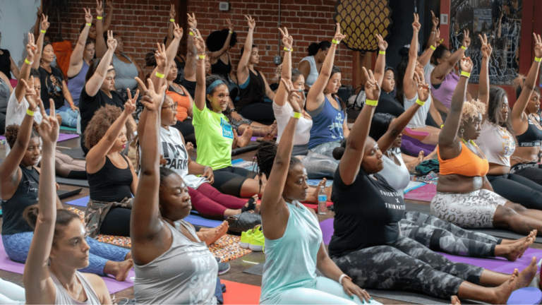 Yoga event participants sit on mats