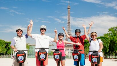 A group raises their hands while riding Segways in front of the Eiffel Tower in Paris, France